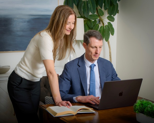 Colin and Cindy Brown reviewing a legal reference at Colin's desk in the Vindex Law office